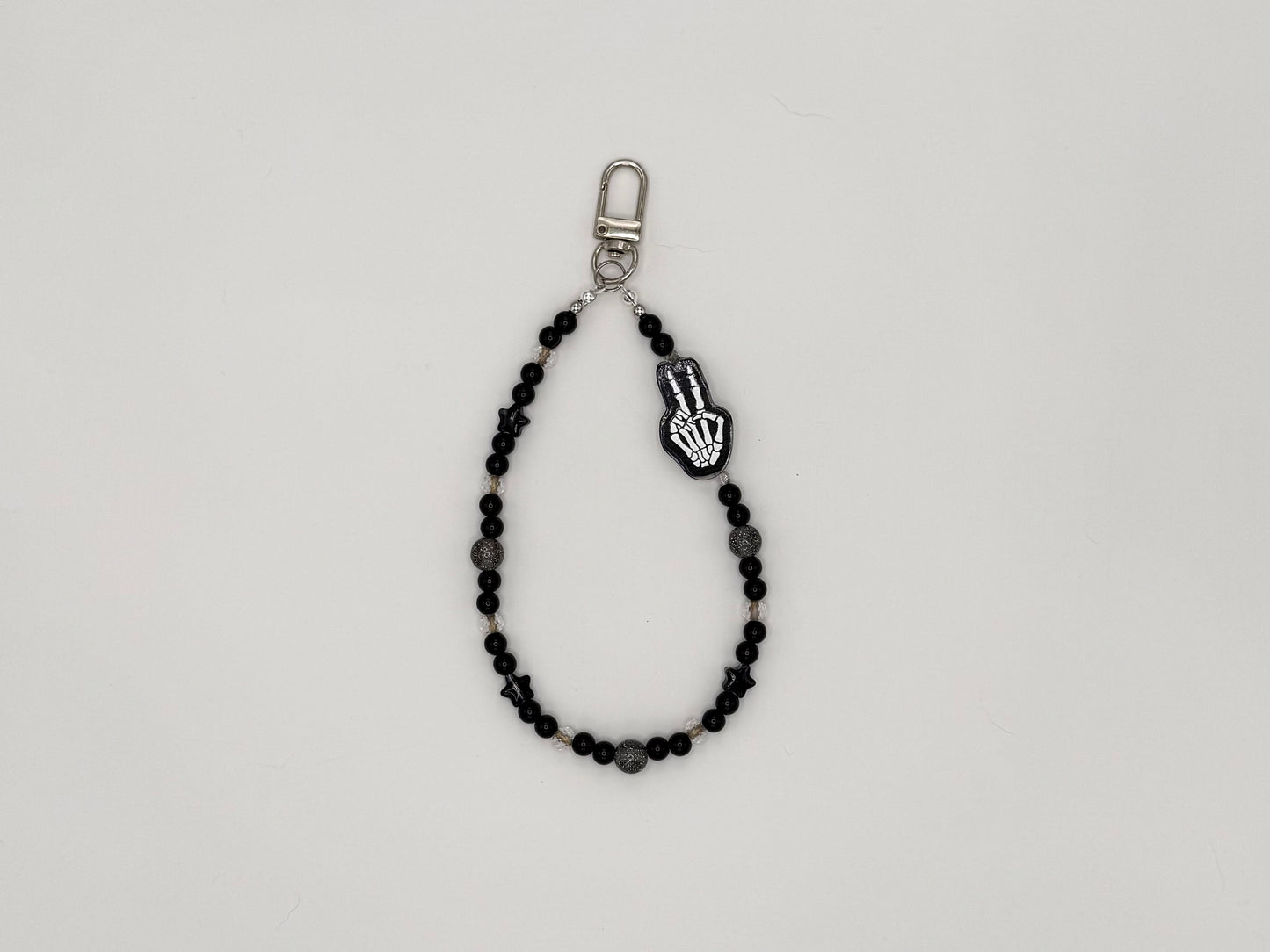 Black beaded keychain wrist strap with skeleton hand peace sign charm and silver swivel clip.