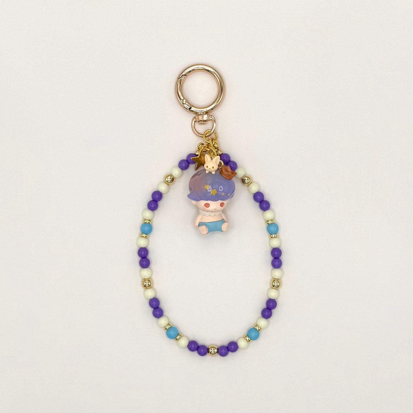 Beaded keychain with a small figurine on a light gray background
