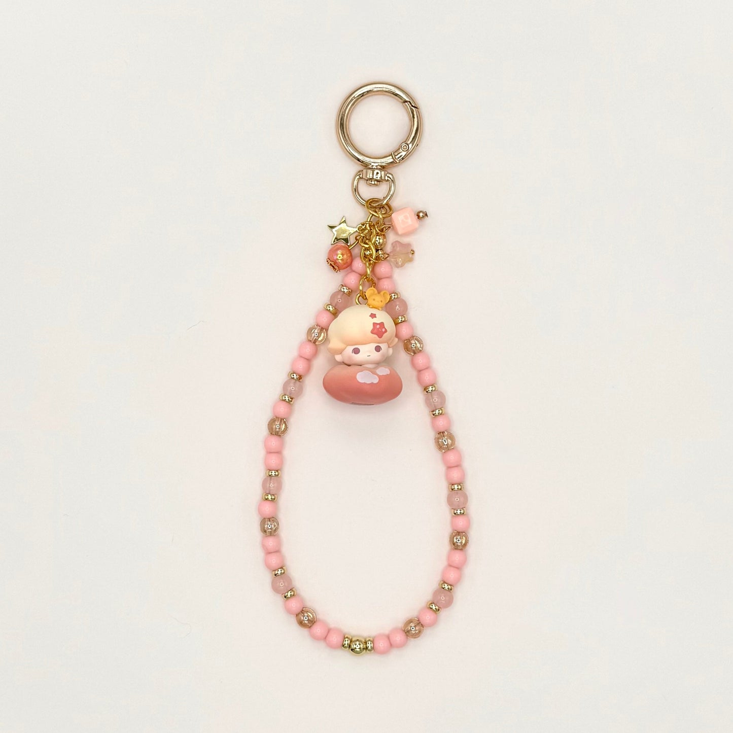 Pink beaded keychain with a small plush toy on a white background