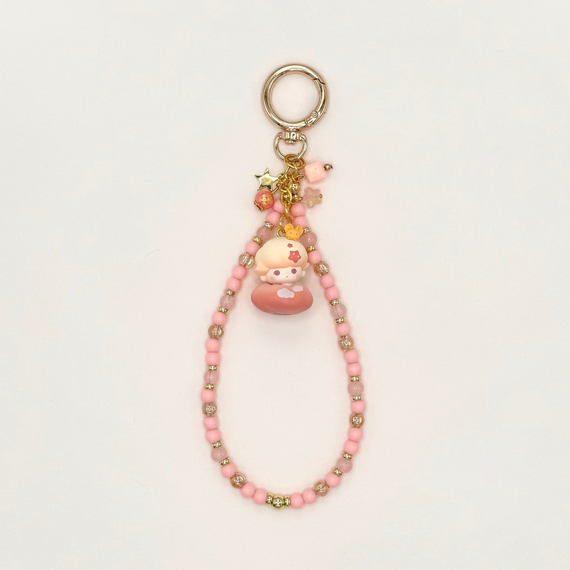 Pink beaded keychain with a small plush toy on a white background