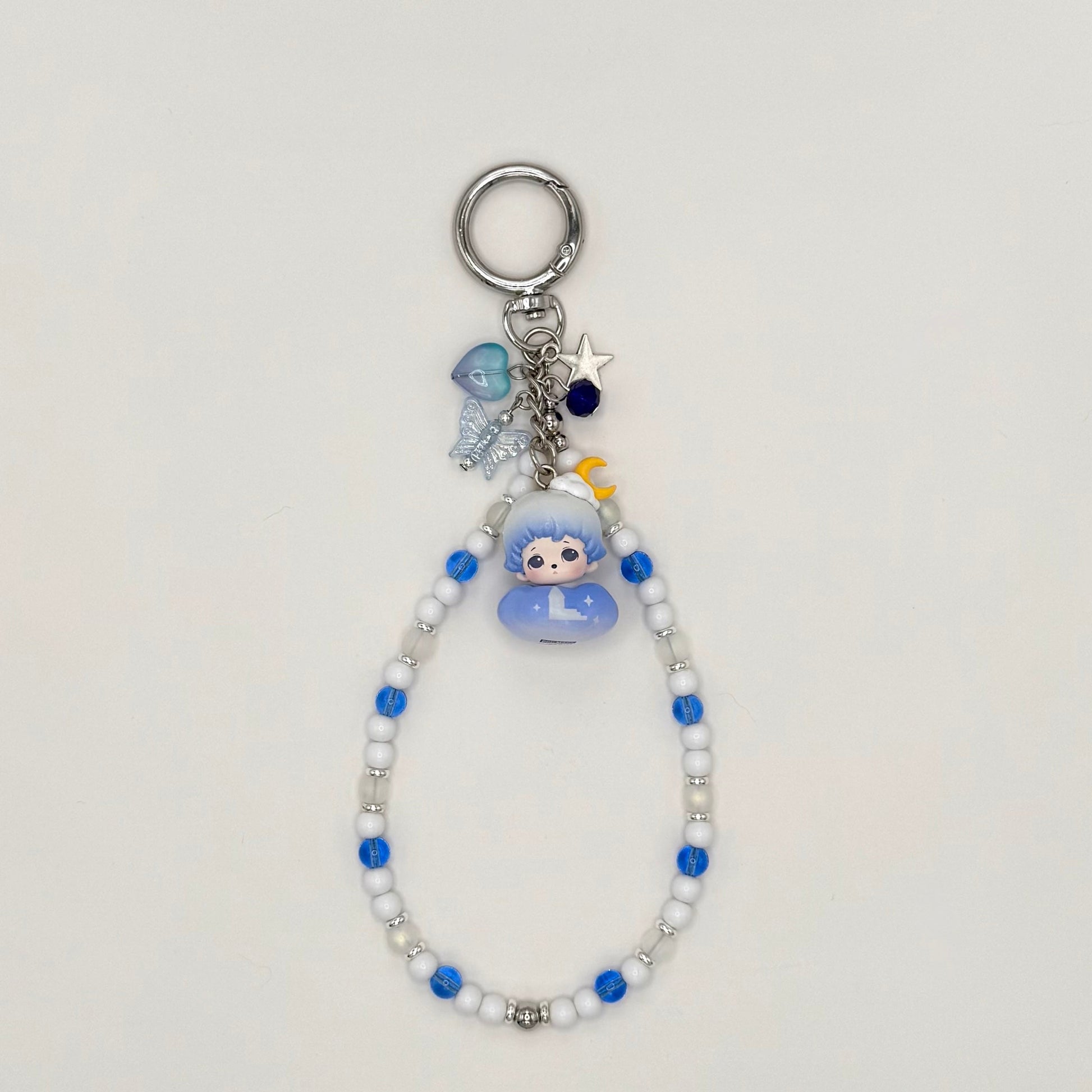 Keychain with beads and a small figure toy on a light gray background