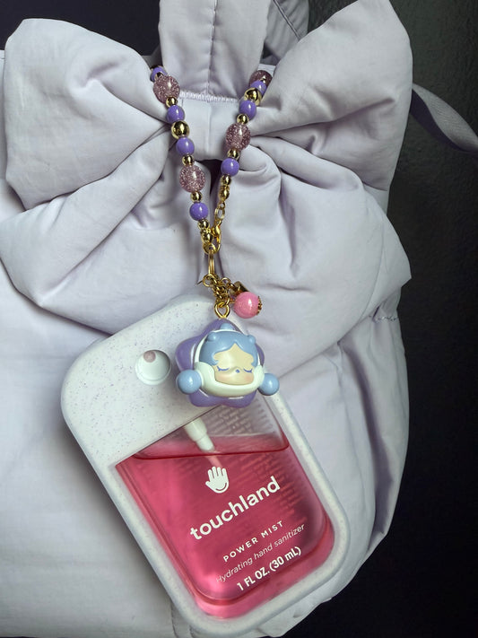Touchland Power Mist hand sanitizer in a white glitter silicone case on a white background. Attached gold lobster clasp keychain features a red-cloaked SP chibi charm with a round face, paired with a beaded wrist strap of alternating red and silver glitter beads with gold accent beads. TOUCHLAND NOT INCLUDED WITH THIS PRODUCT!
