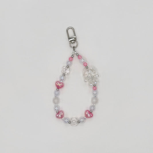 Phone wrist strap with pink heart-shaped beads, frosted white round beads, clear crystal bicone beads, and silver spacers, featuring a clear transparent character charm, on a silver swivel clasp."\