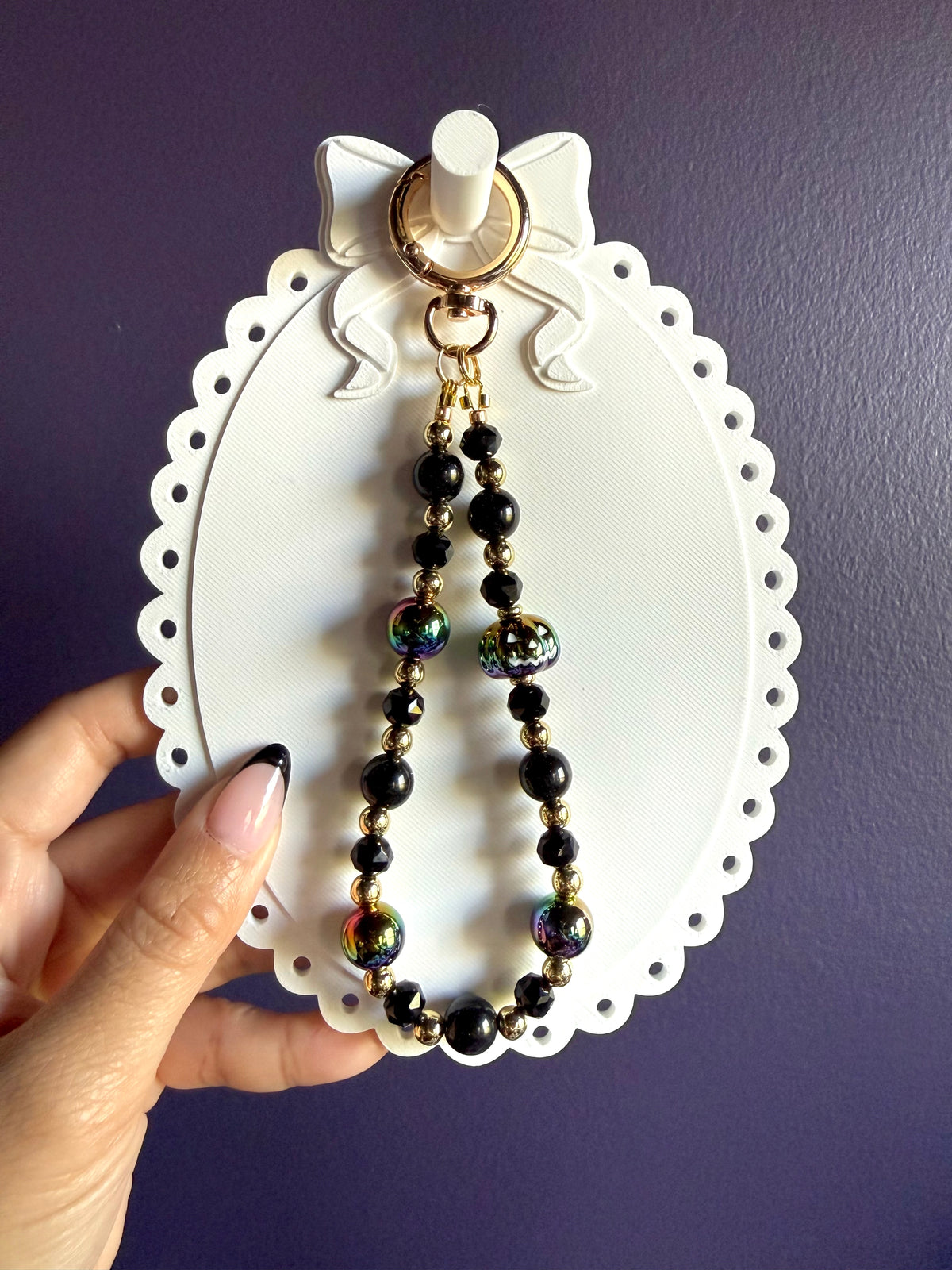 Black beaded wristlet keychain with an iridescent jack-o’-lantern bead, rainbow-finish round beads, and gold-tone accents.