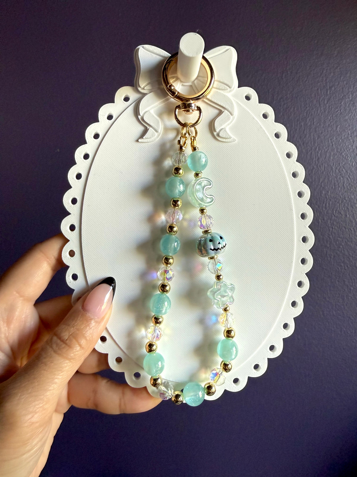Pale blue beaded wristlet keychain with a blue jack-o’-lantern bead, translucent moon and star beads, and gold-tone accents.