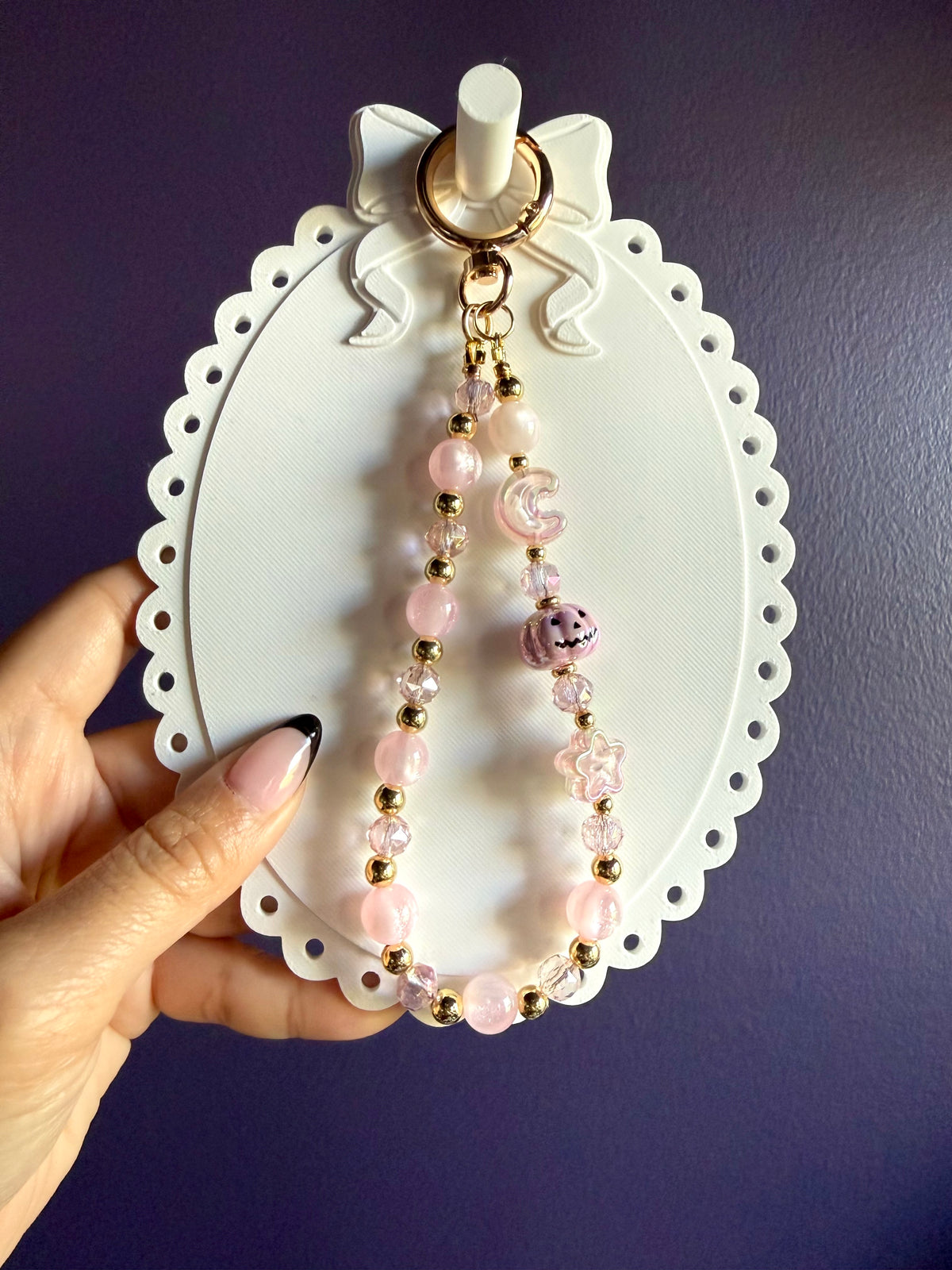 Pale pink beaded wristlet keychain with a pink jack-o’-lantern bead, translucent moon and star beads, and gold-tone accents.