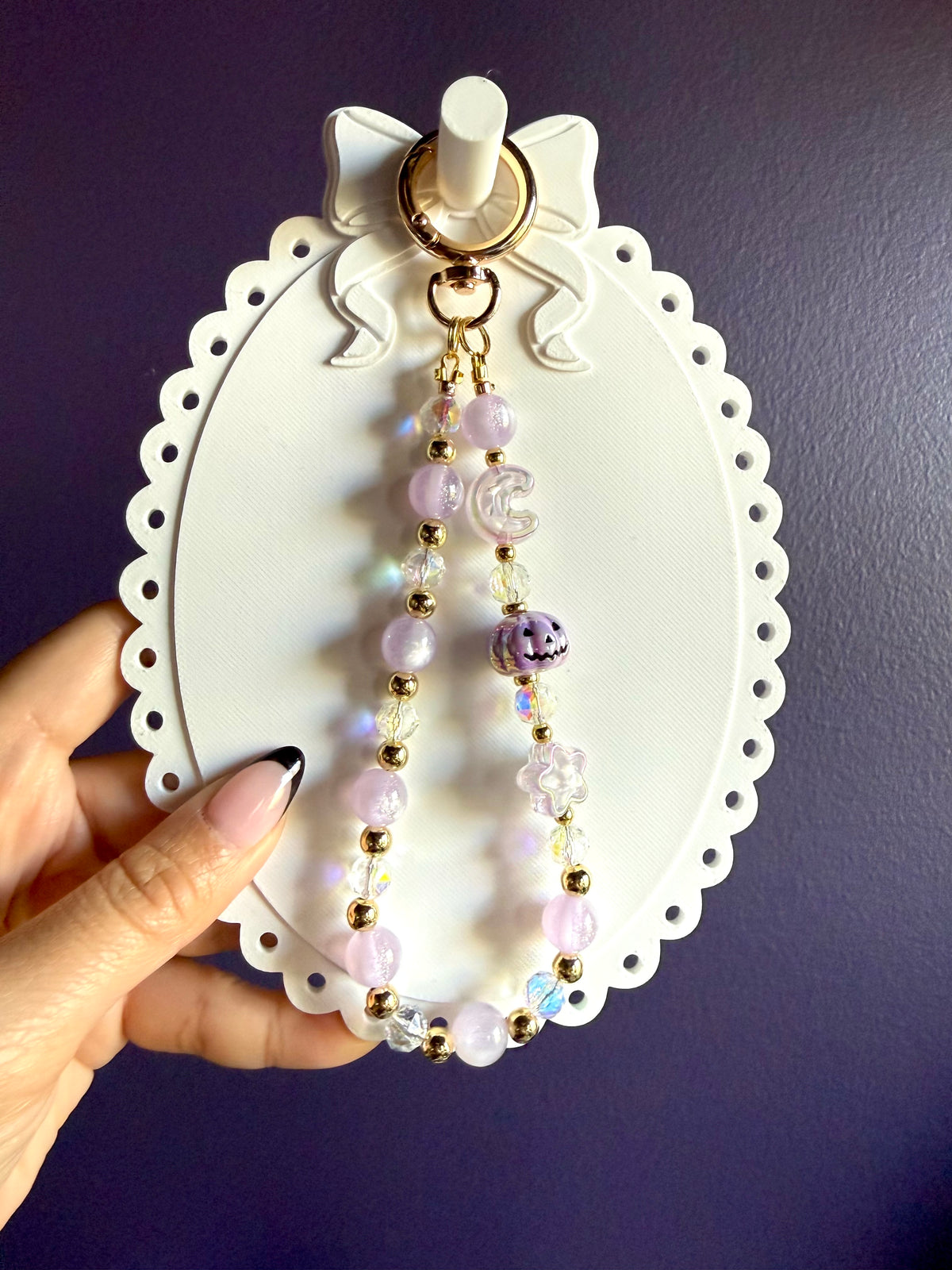 Pale purple beaded wristlet keychain with a purple jack-o’-lantern bead, translucent moon and star beads, and gold-tone accents.