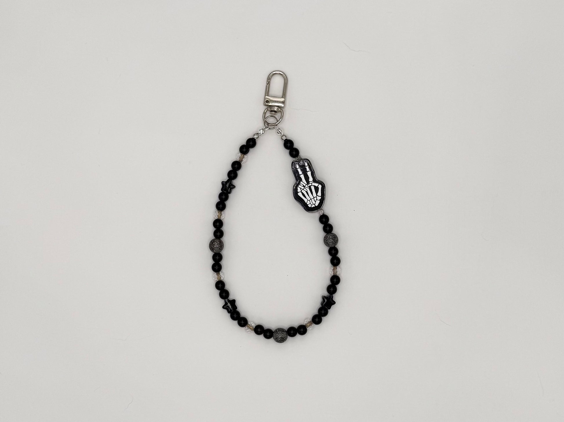 Black beaded keychain wrist strap with skeleton hand peace sign charm and silver swivel clip.