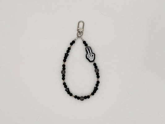 Black beaded keychain wrist strap with skeleton hand peace sign charm and silver swivel clip.